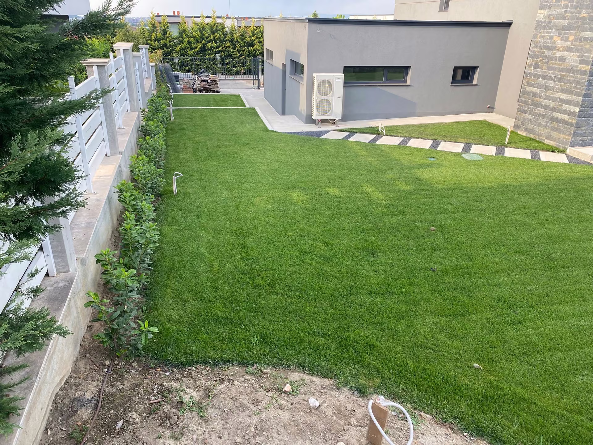 Césped y valla blanca junto a una vivienda contemporánea